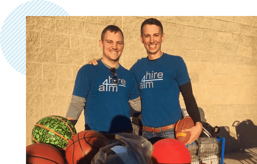 Two men standing next to each other holding basketballs.